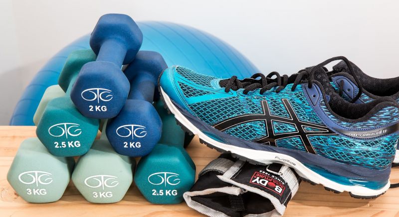 Image of exercise equipment including dumb bell and running shoes.