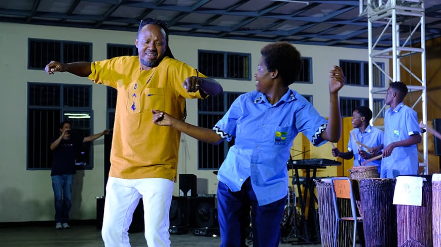 Jacques “Popo” Murigande dances with a student from the School of Arts and Music choir after the performance.