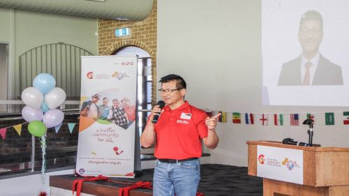 A man holding a microphone giving a presentation in front of a screen