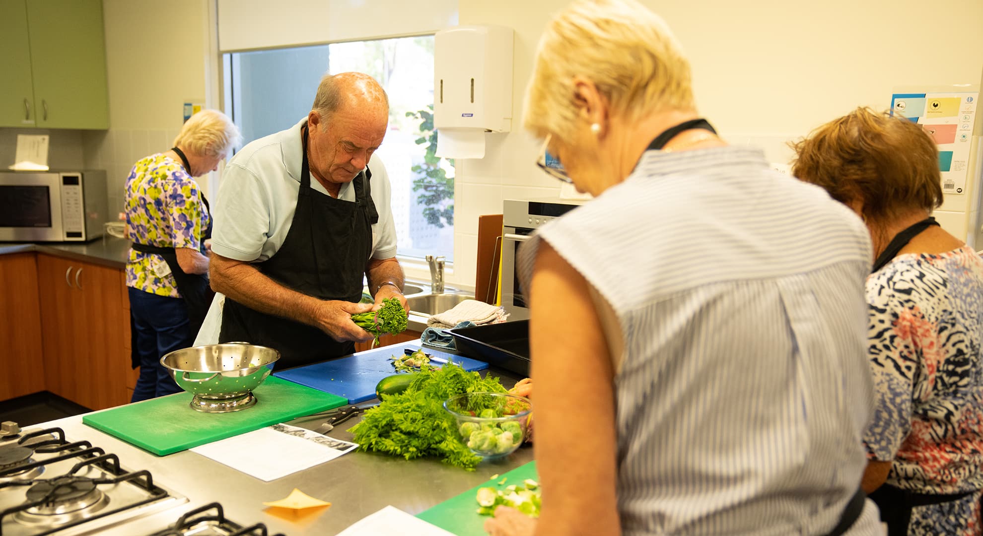 Older man and women preparing vegetables at the workshop.