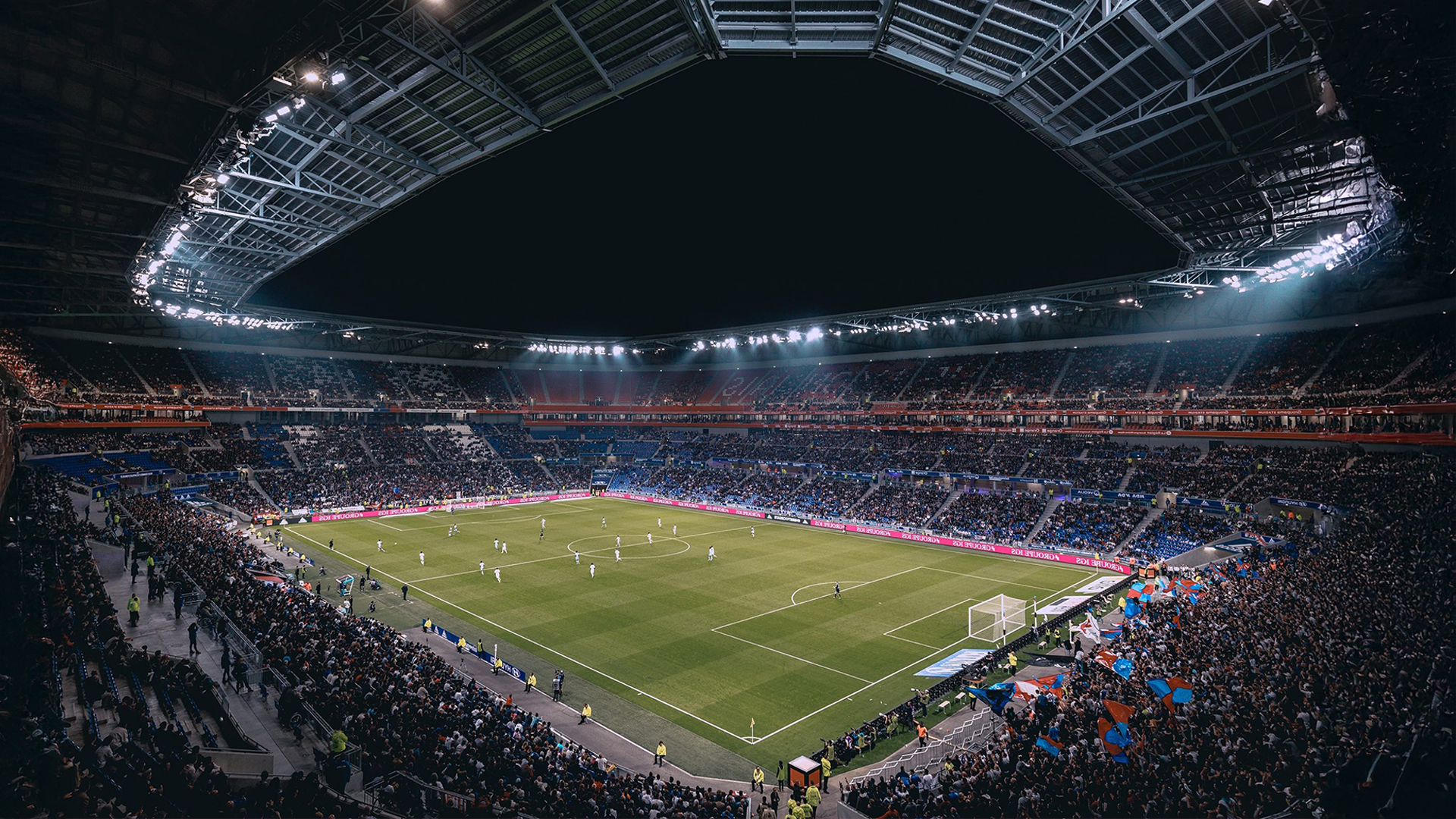 Thousands of spectators at a sport stadium watching a game of soccer