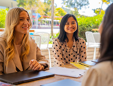 Students engage in conversation outdoors in a university setting.