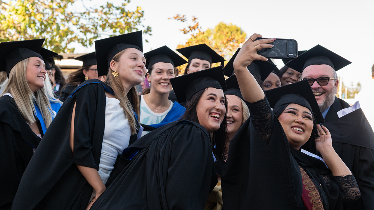 A group of graduating students pose for a selfie