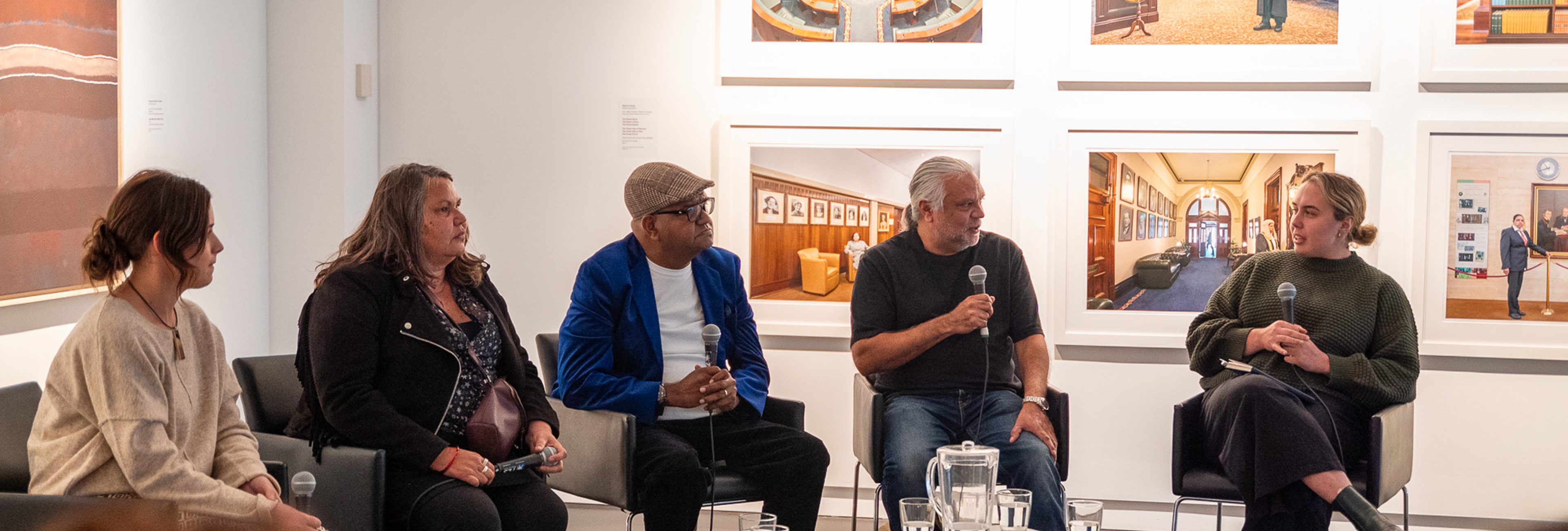 Five people sitting on chairs and holding microphones having a panel discussion
