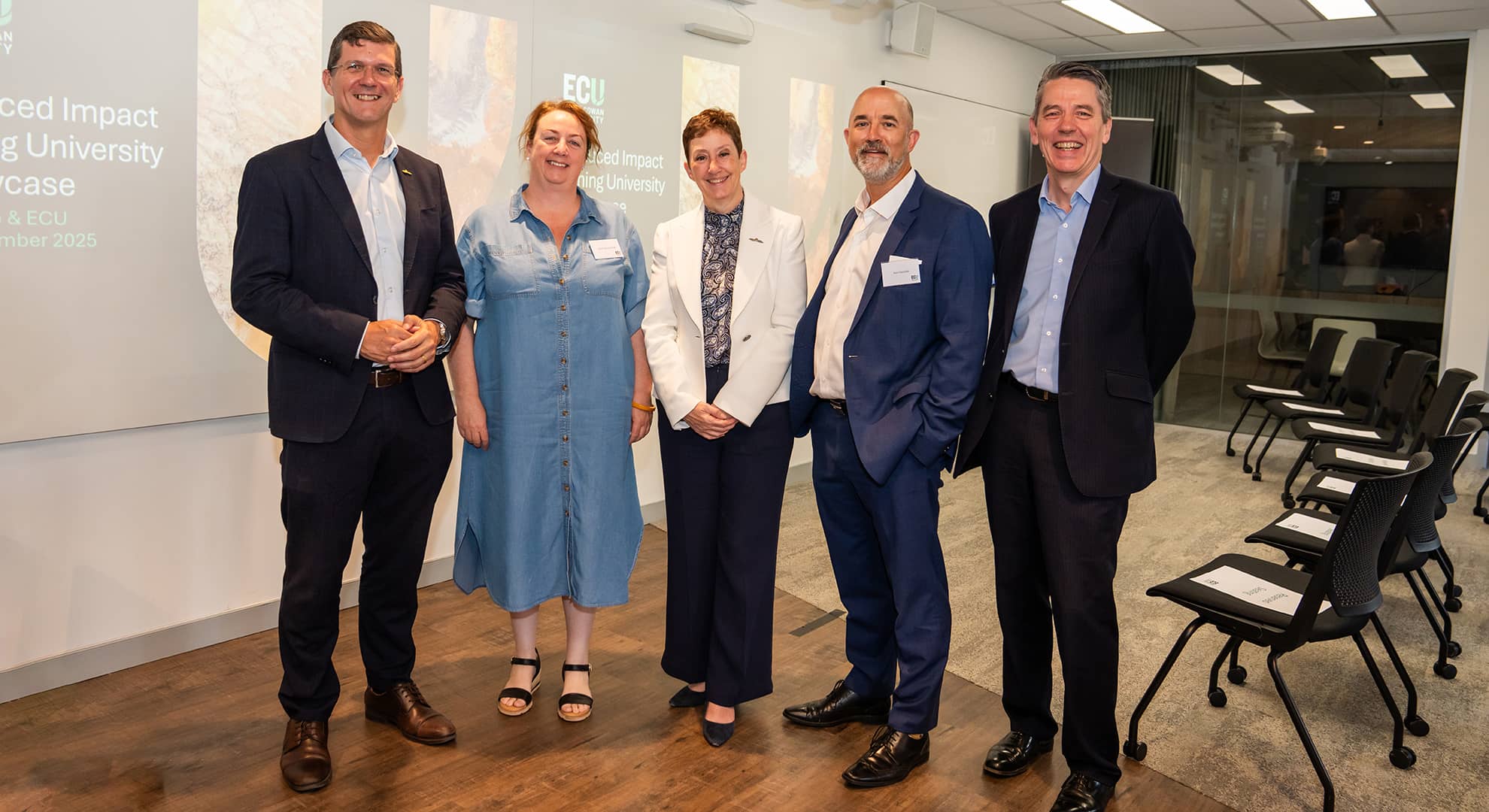 Five people standing facing the camera, smiling.