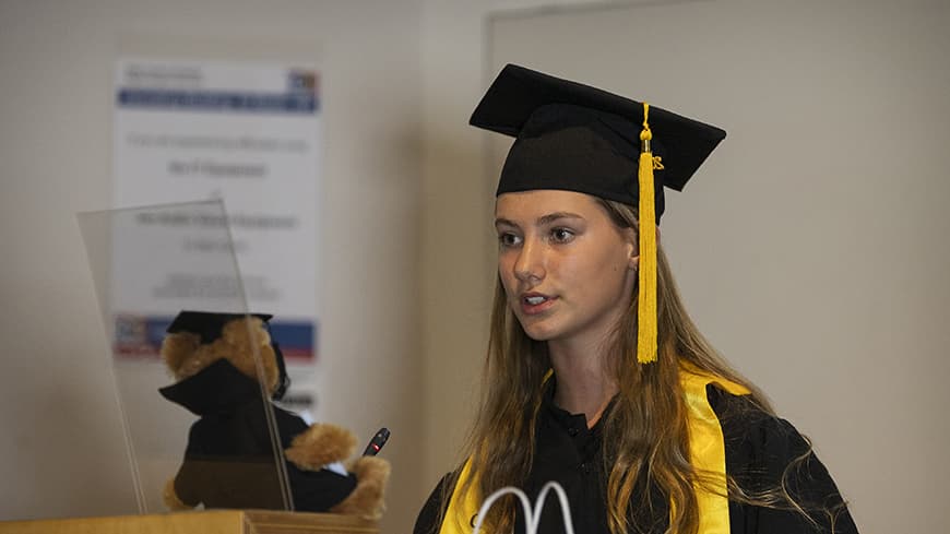 Student Lara Rodgers stands at lectern to deliver a speech to the graduating class