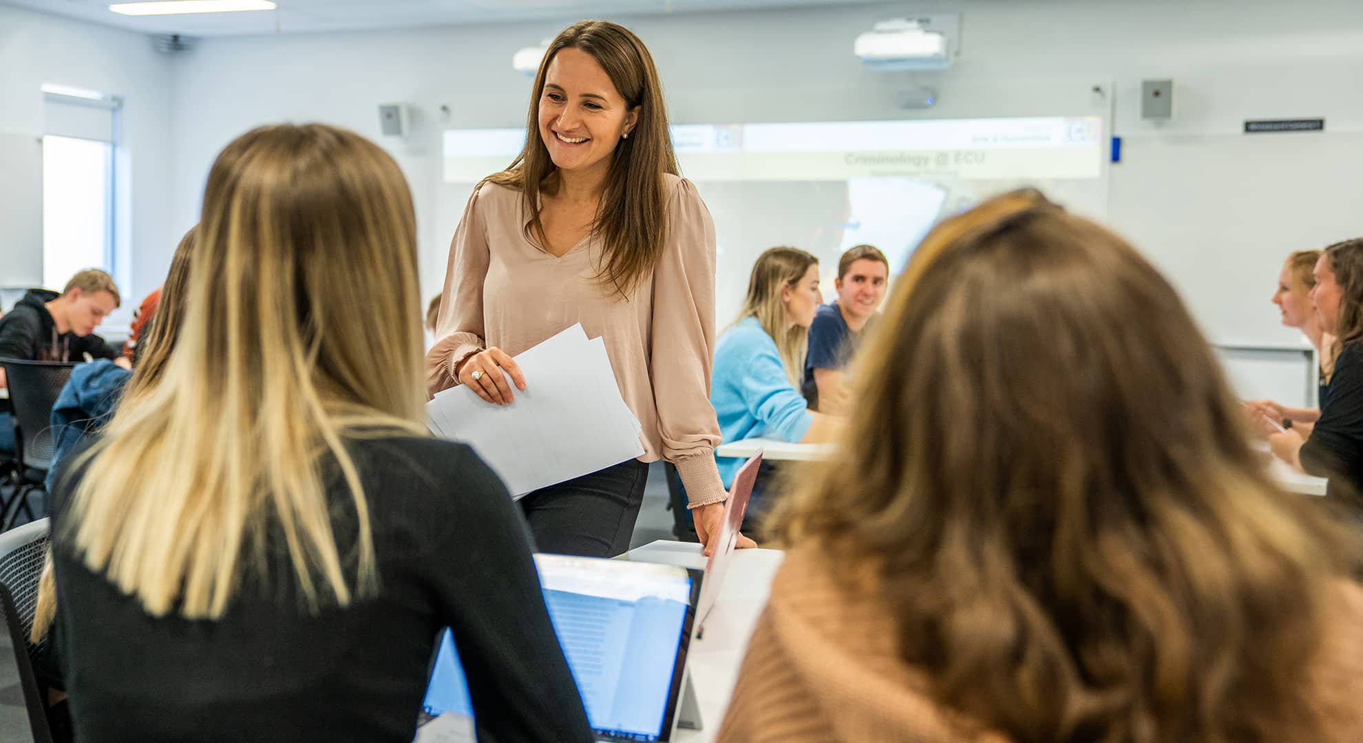 A woman standing with a group of students, smiling.