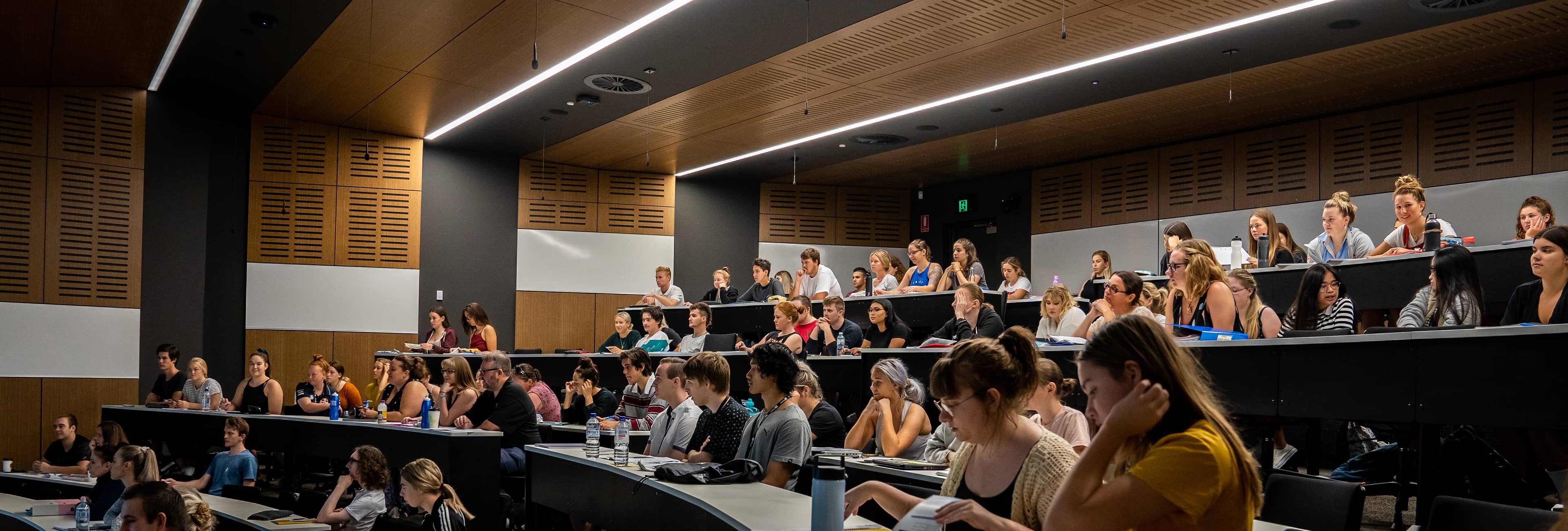 A wide shot of an audience of students in a lecture theatre