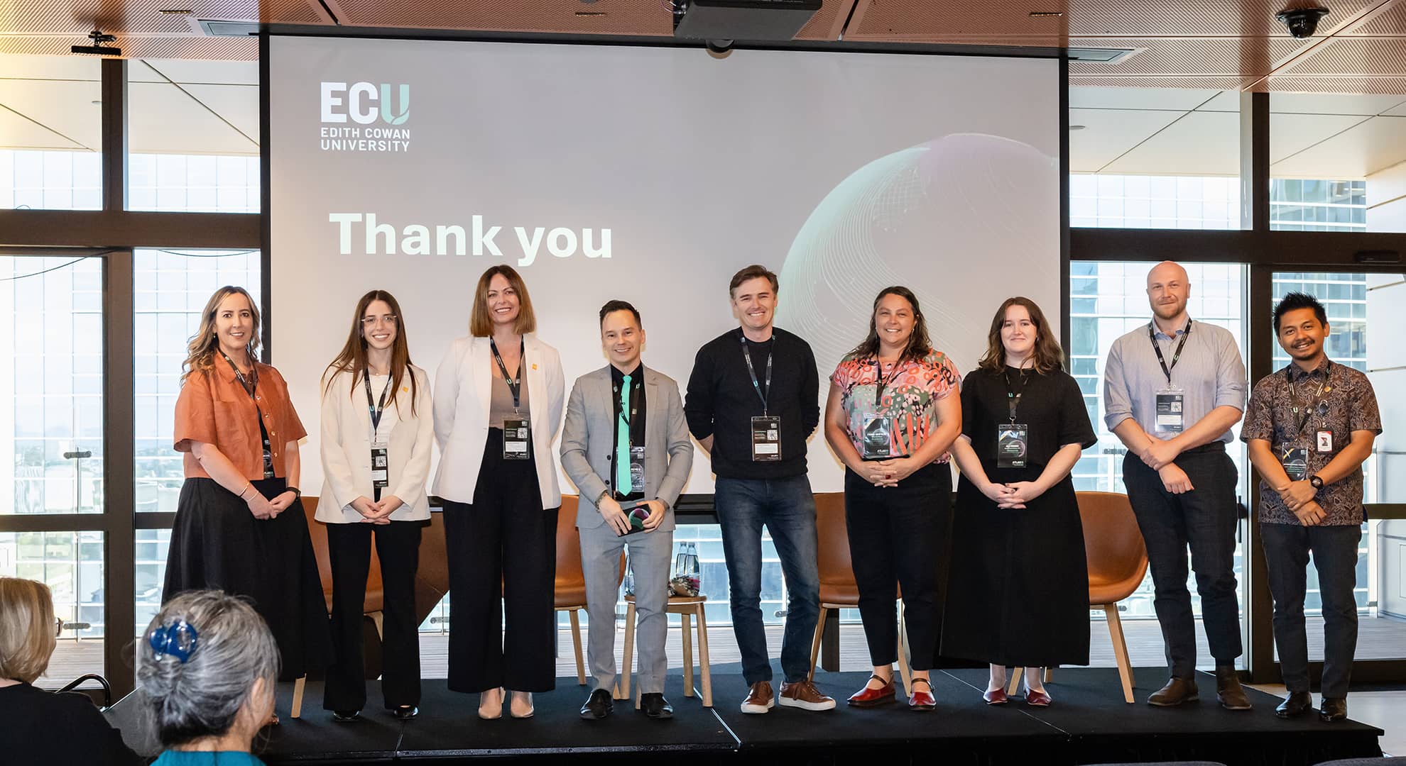 People standing on stage facing the audience at a conference