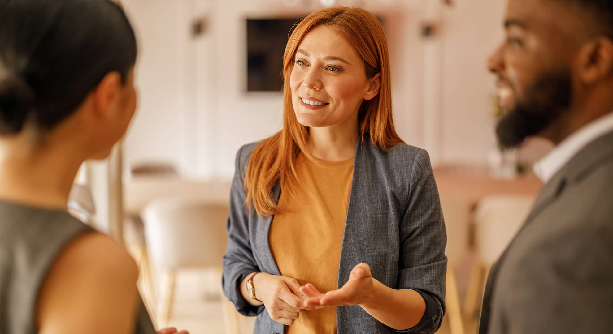 Smiling female manager discussing and explaining project strategies with business colleagues in office.