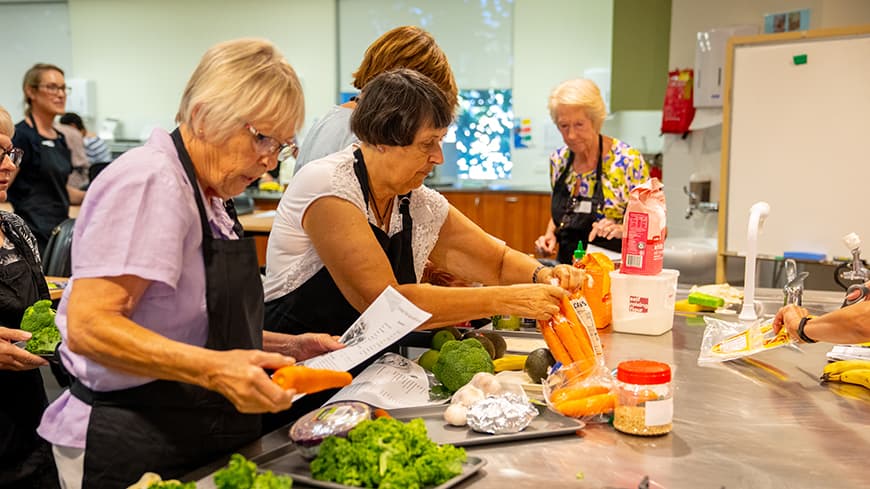 Older women preparing vegetables at the workshop.
