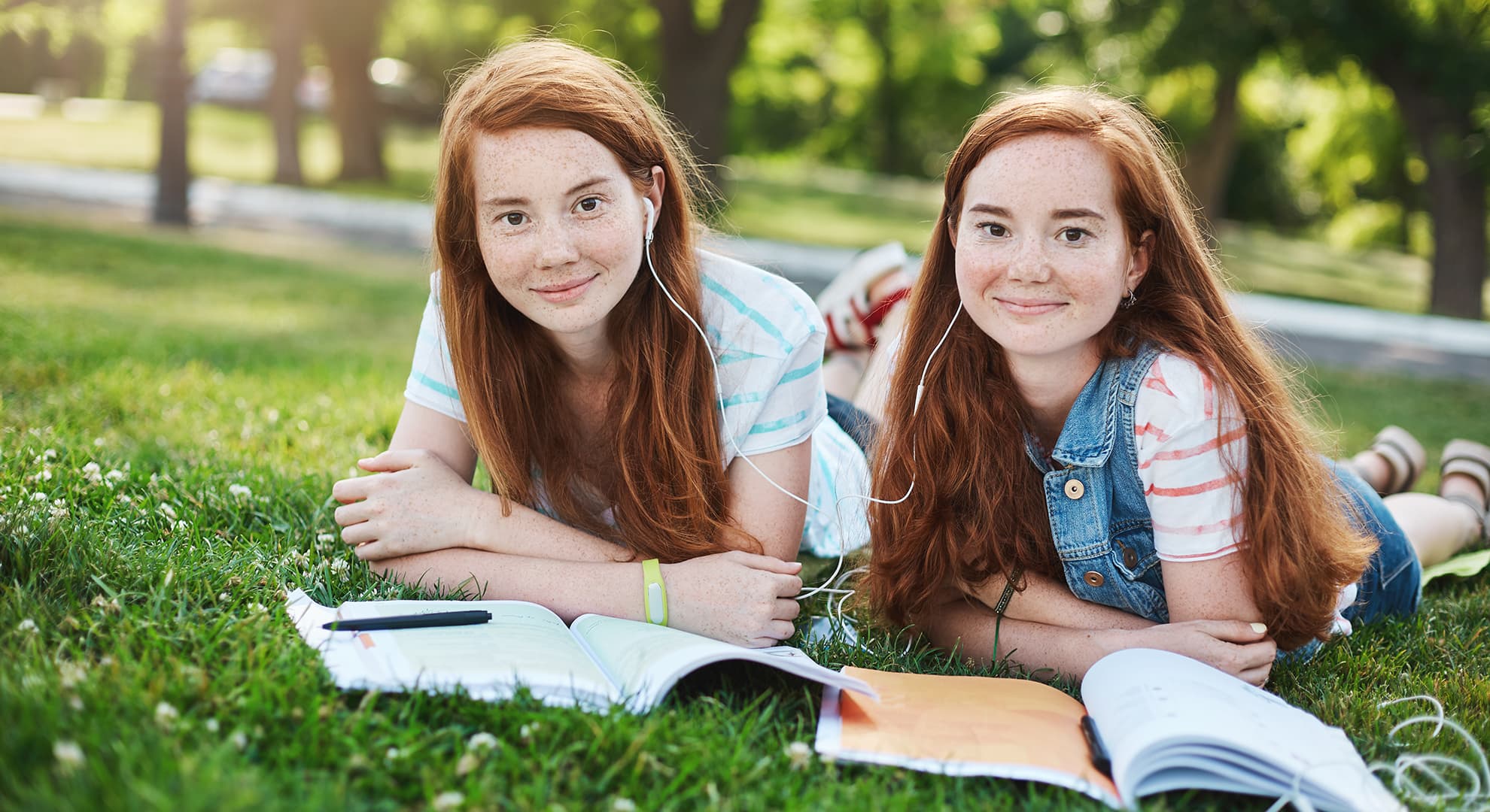 Twin female students laying on grass