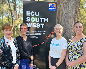 4 people standing at an ECU South West sign smiling