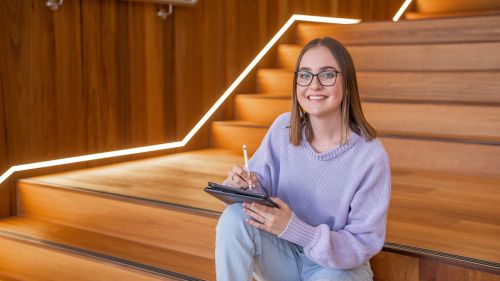 Students writing notes while sitting on steps
