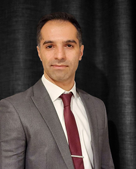 Photo of a male Research Associate wearing a grey suit and red tie