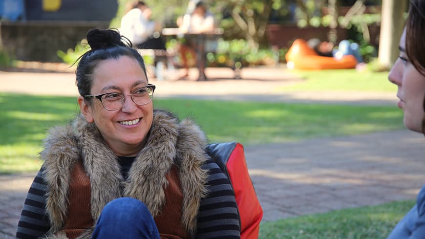 Dr Ange Jones grins as she sits outside talking to her colleague.