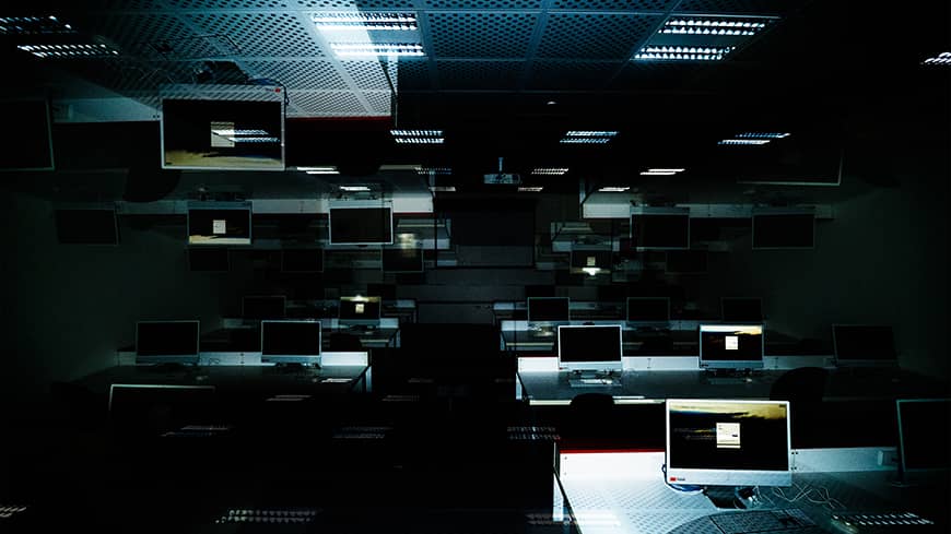 An abstract image of a faintly lit classroom showing computer screens on desks