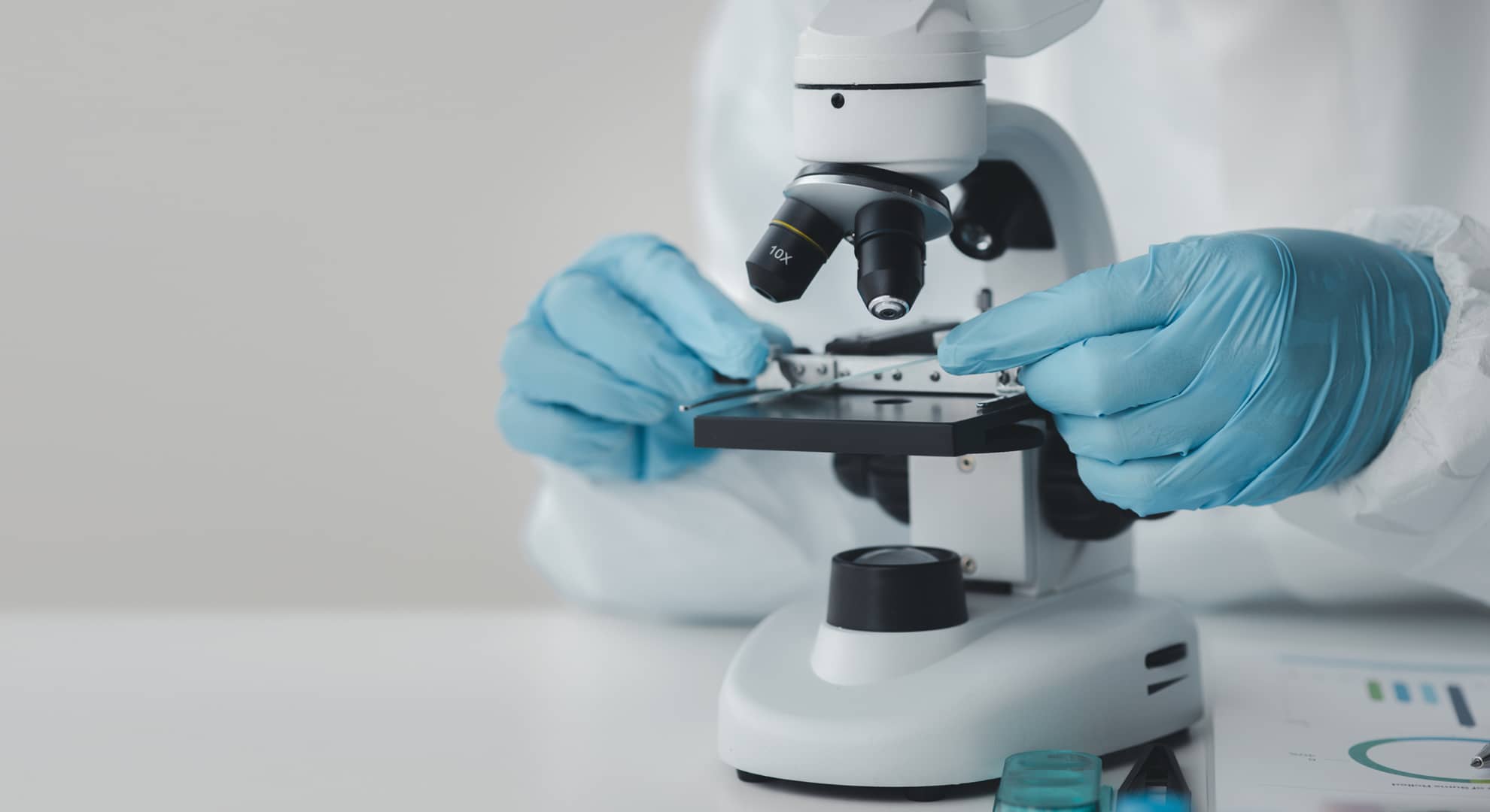 Hands next to a microscope.