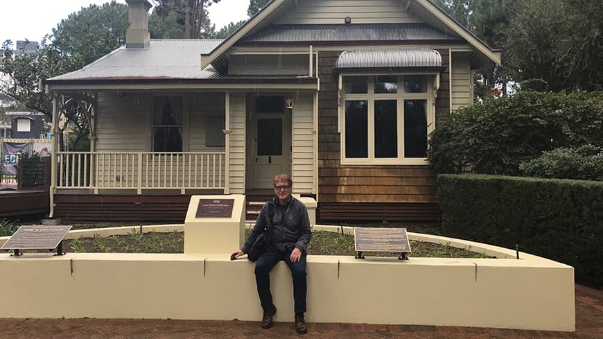 A man sitting in front of a historic house.