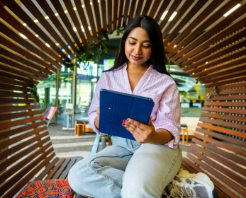 Student sitting in a wooden study space using a tablet to access digital resources
