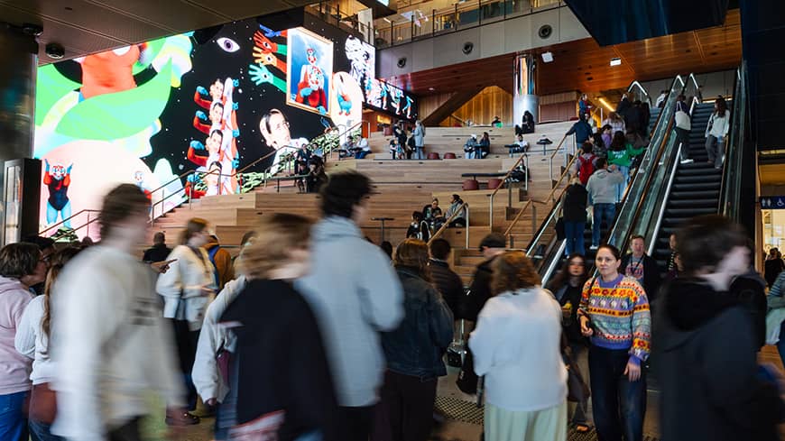 Visitors using the escalators and sitting on steep steps inside the building