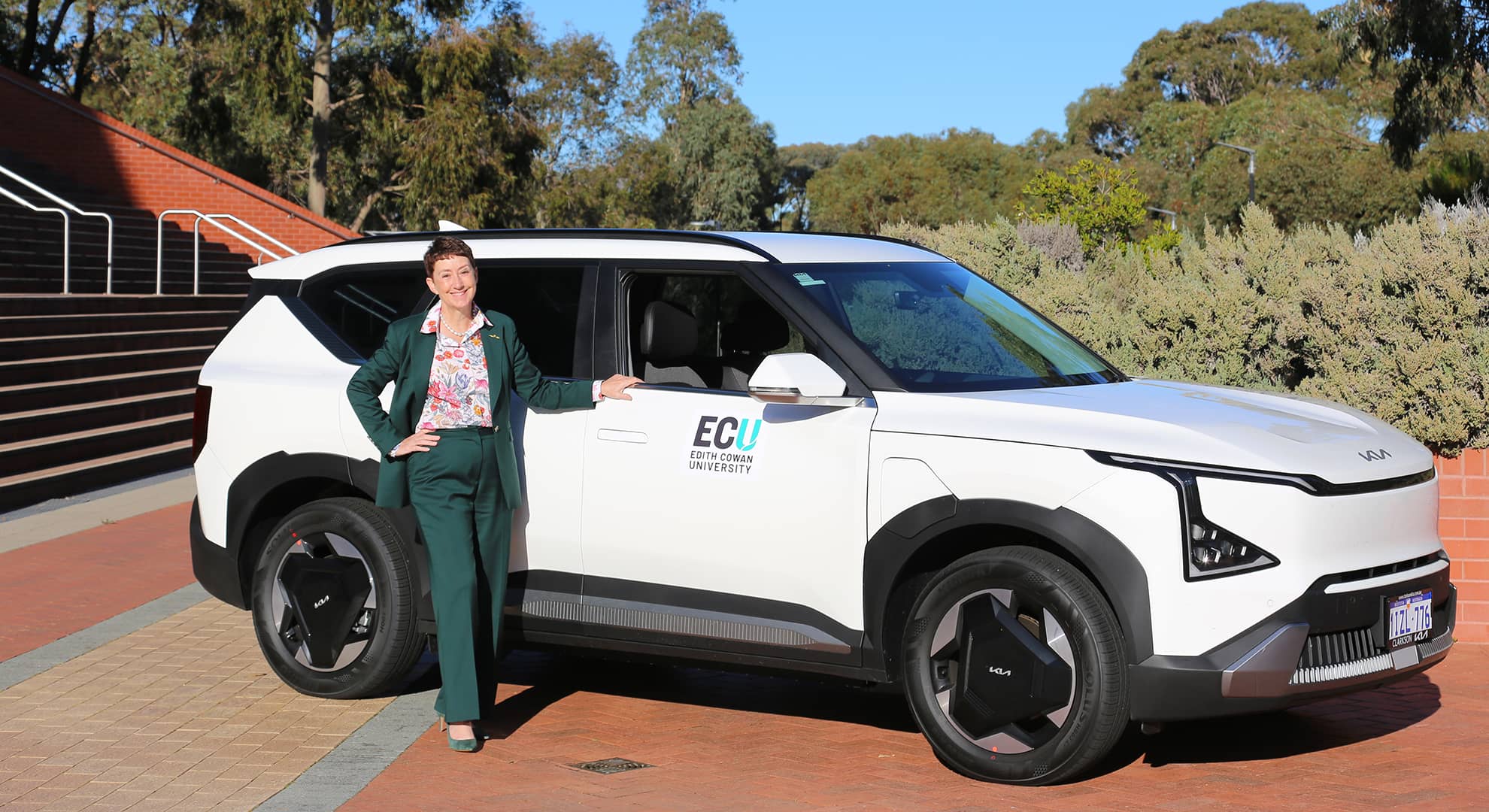 Professor Clare Pollock standing in front of one of the new EVs