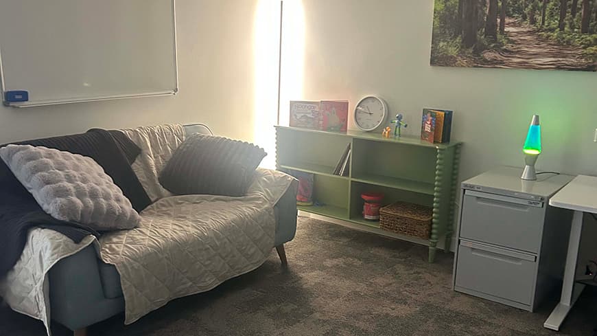 The low sensory room, with a couch and a bookcase with toys.