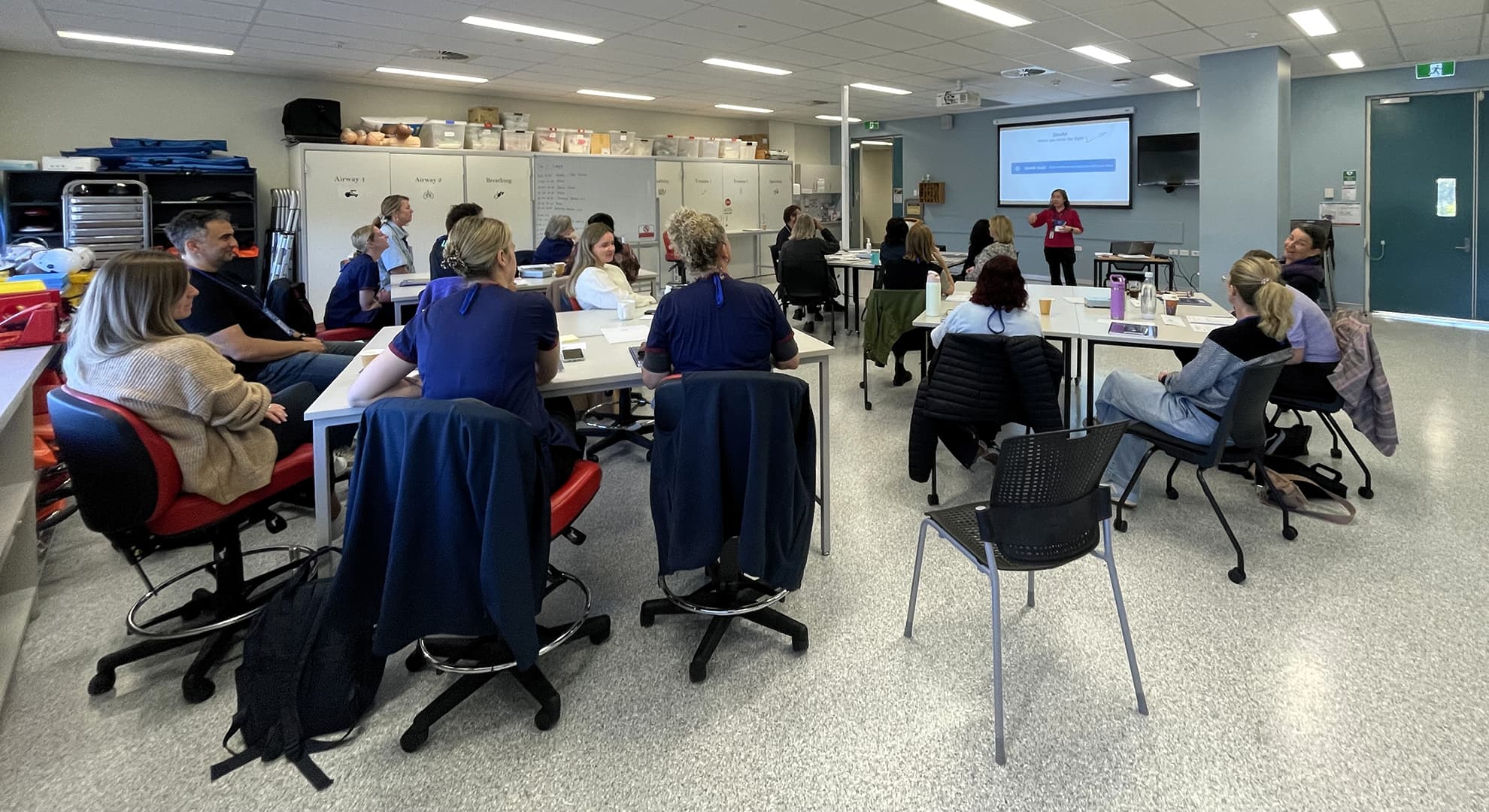 Classroom showing course participants and a lecturer at a whiteboard