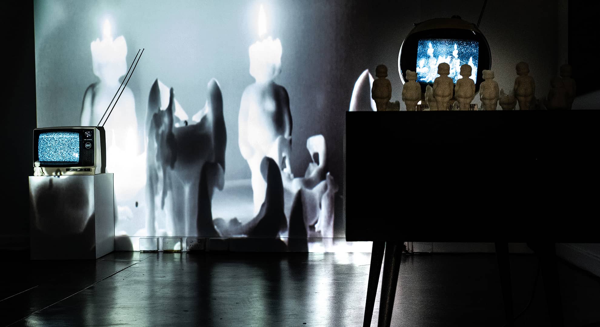 Kat Chaplin's artwork Staring at the Sun, showing indistinct, shadowy figures and a TV with white noise on the screen