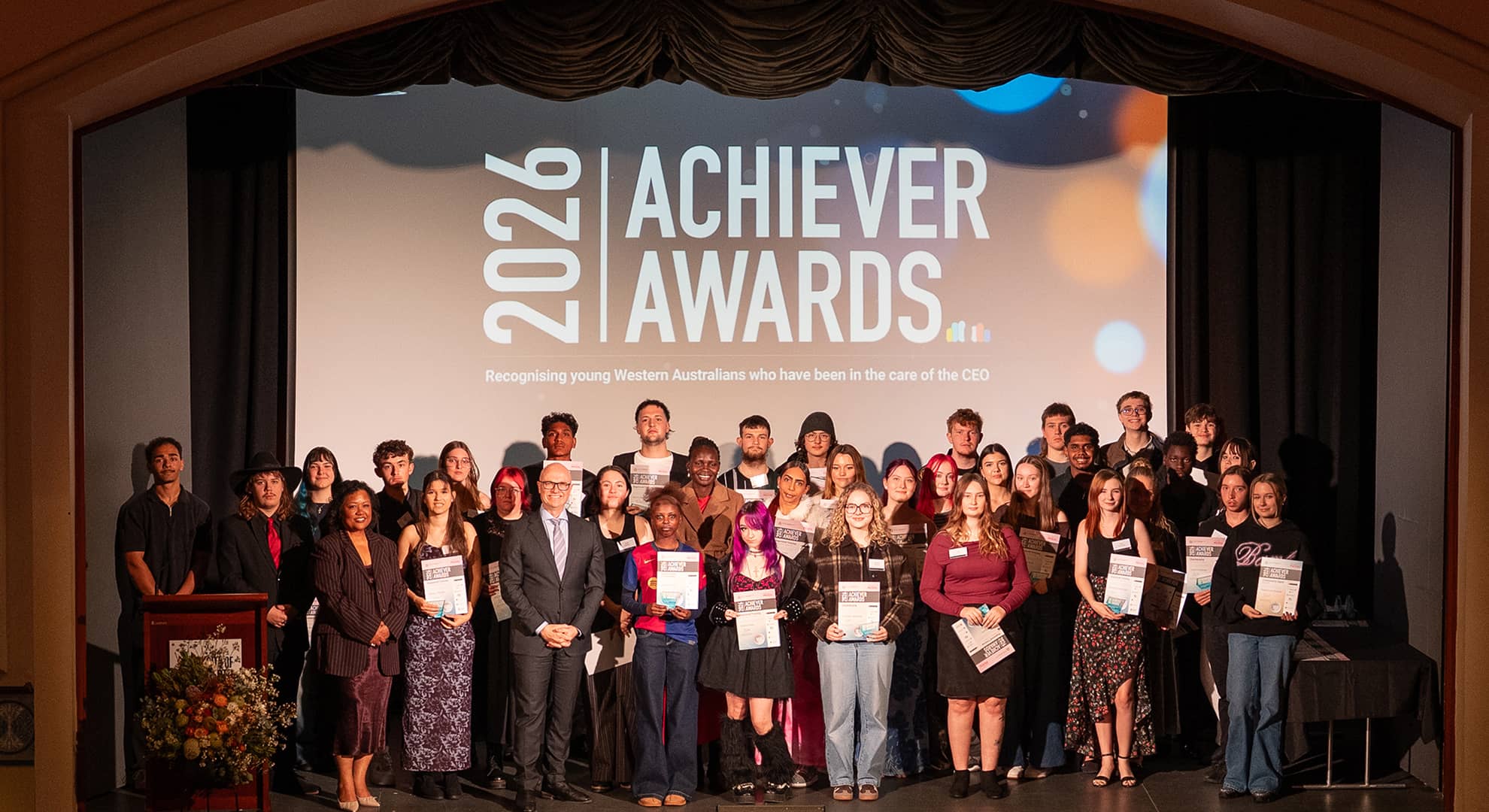 A number of young people on stage with certificates.