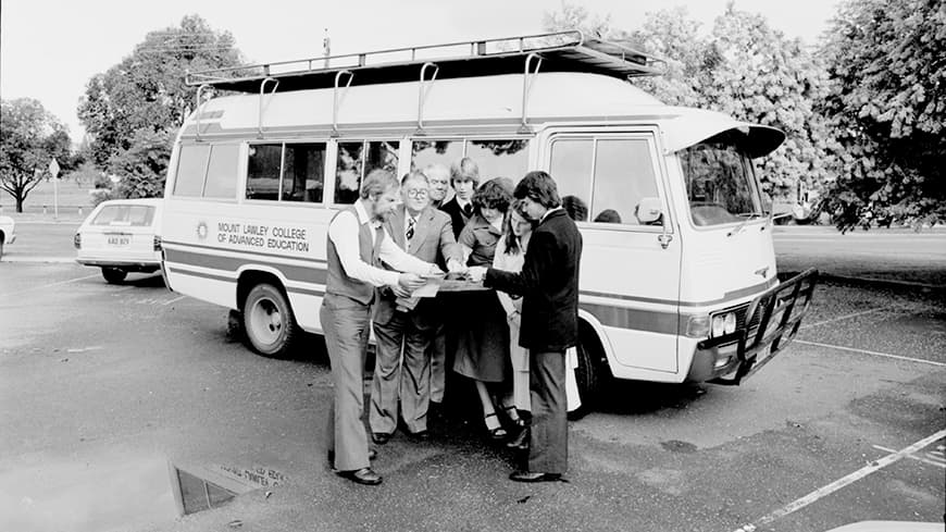 People reading a map in front of a bus.
