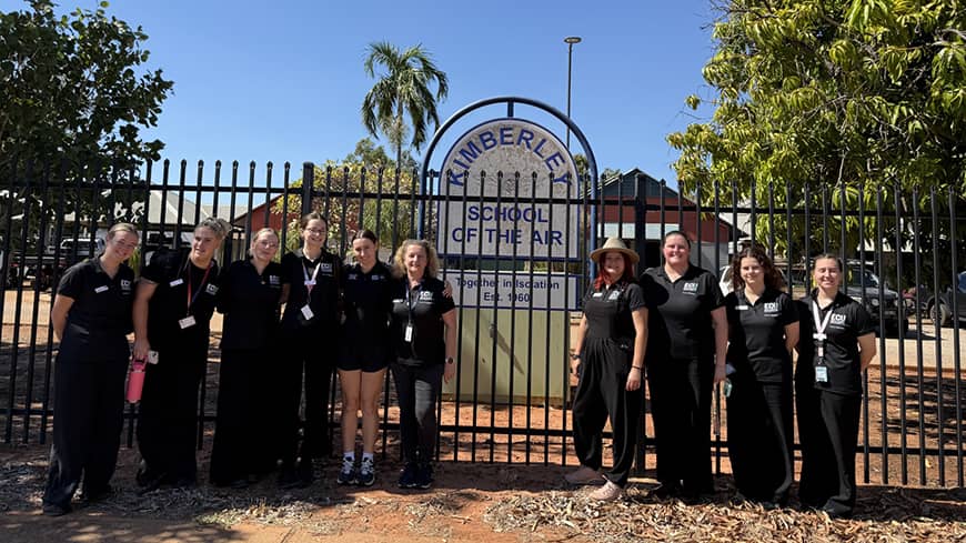 A group of 10 pre-service teachers outside a school