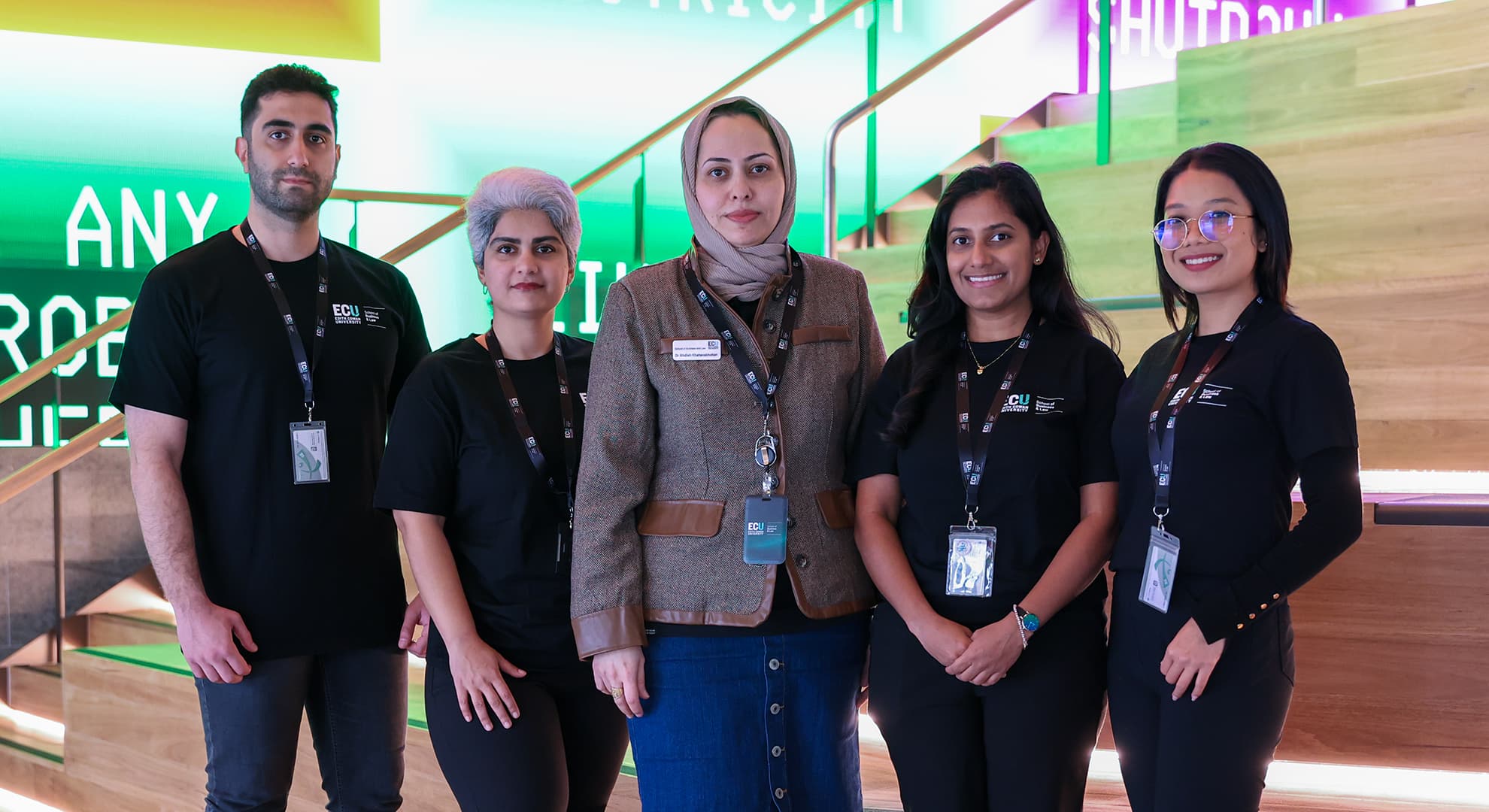 Four students and their lecturer pose on the stairs