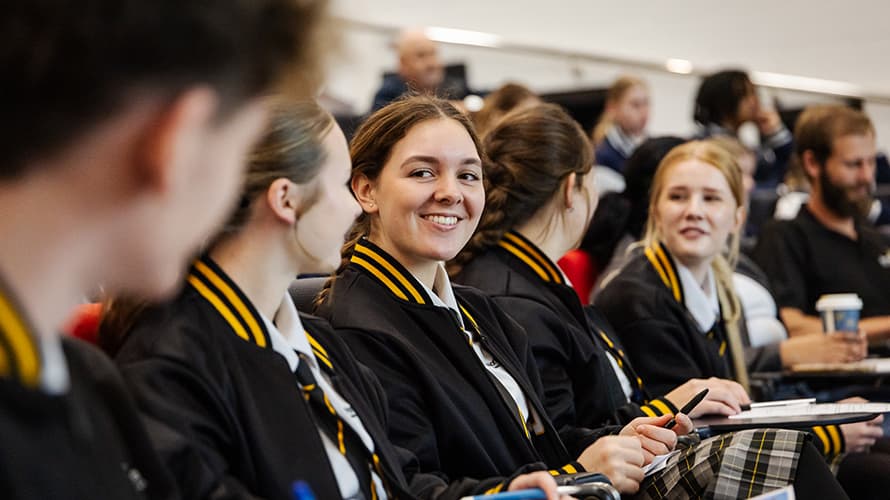 Students smiling and sitting in a lecture theatre