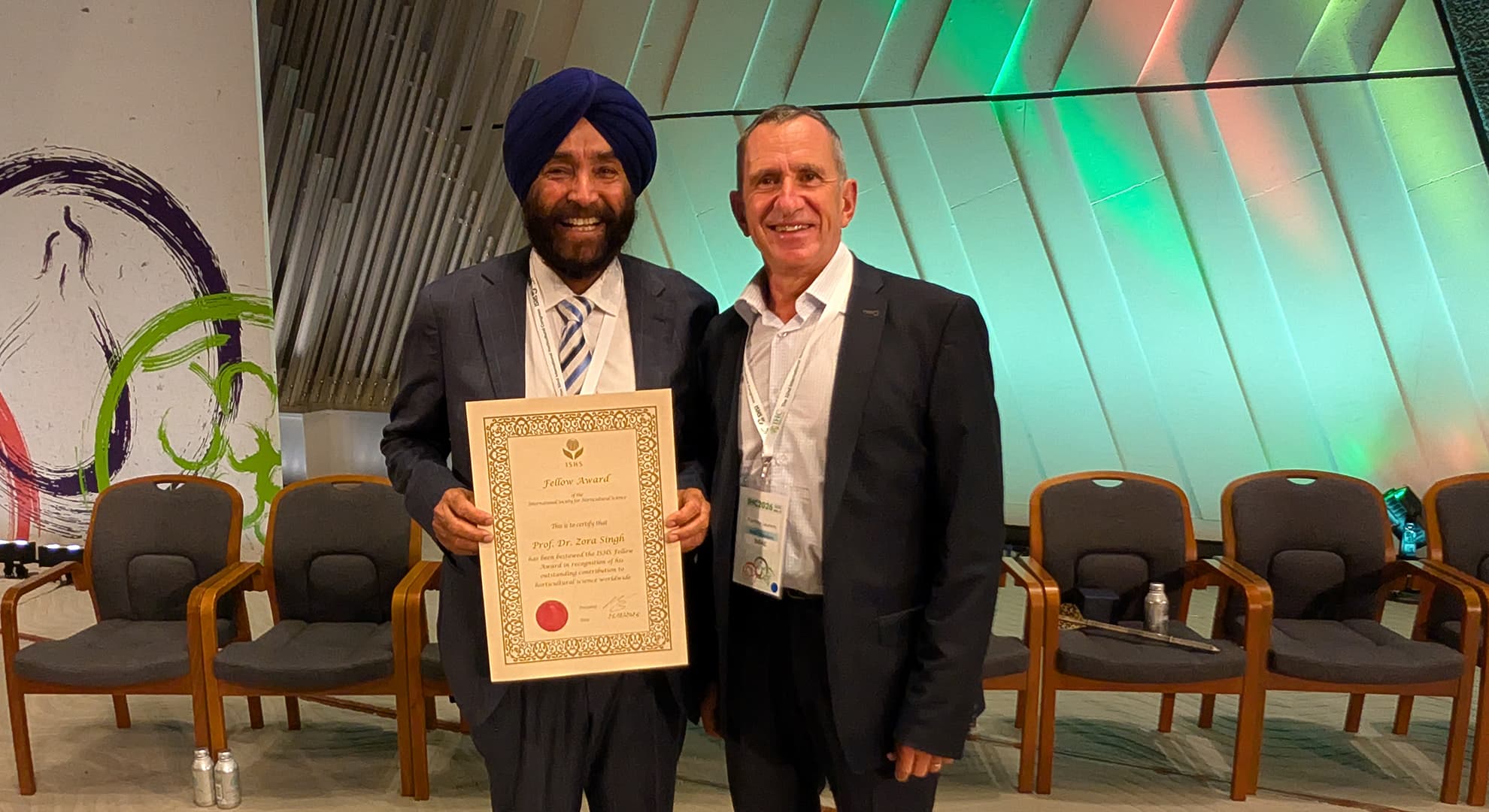 Two men standing with one holding a certificate.