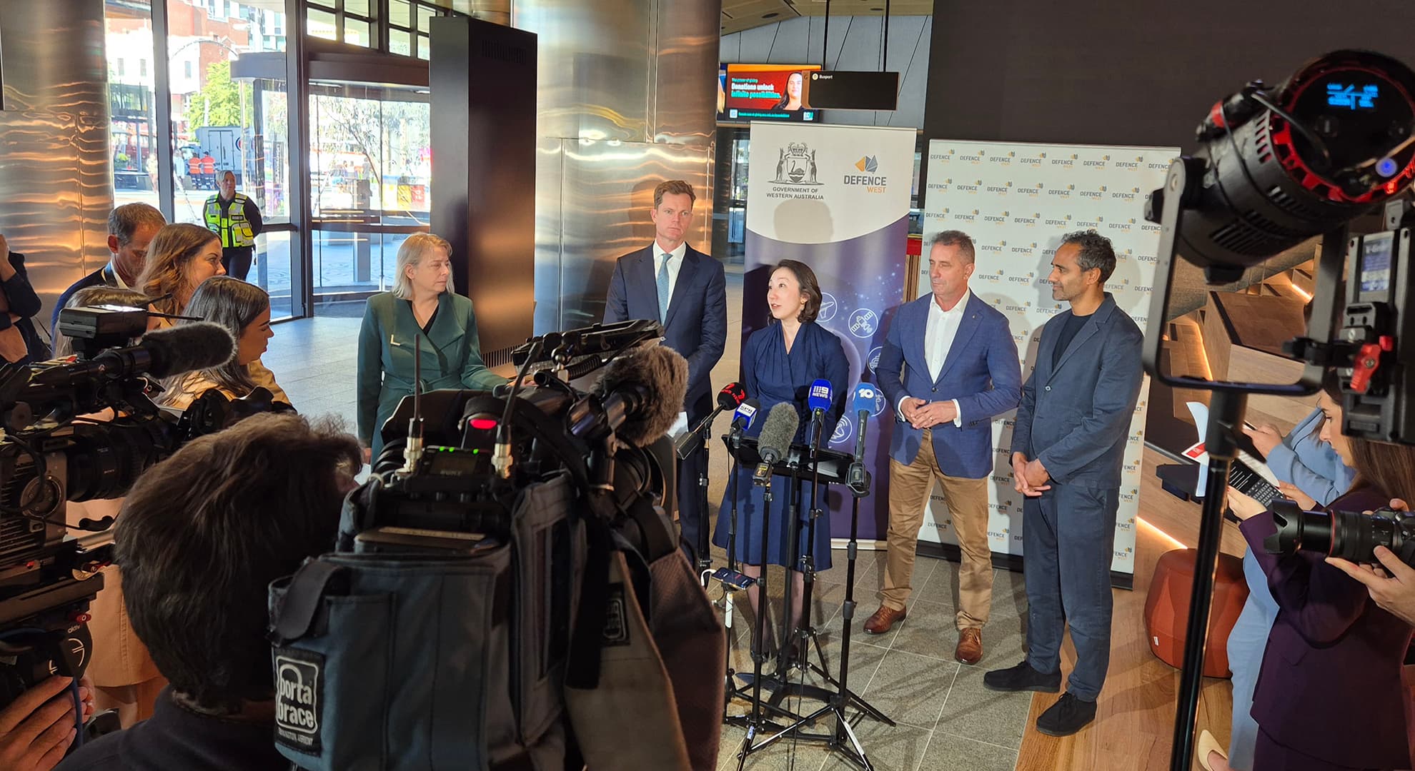 Four people standing in front of a host of journalists and camera operators.