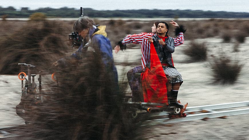 Three people sitting on a moving aparatus.