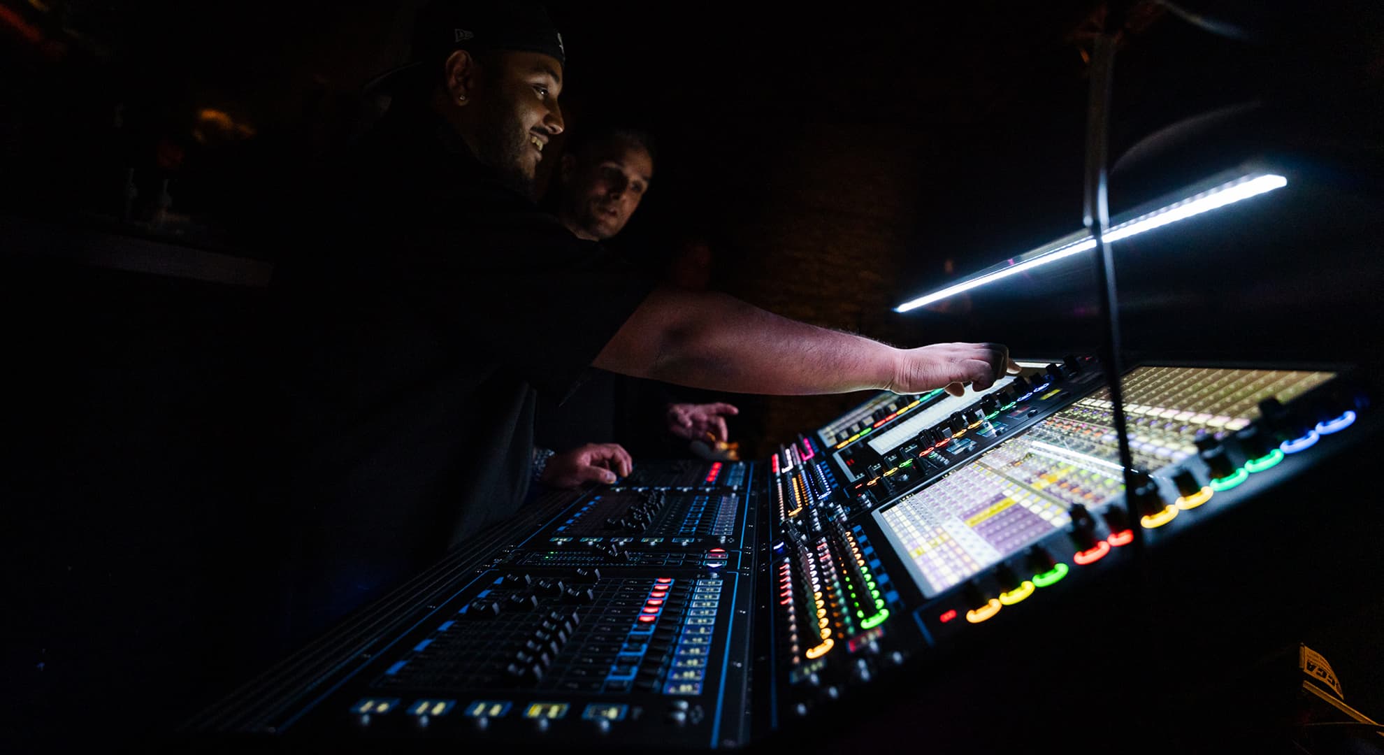 Two people working on a sound/lighting desk.