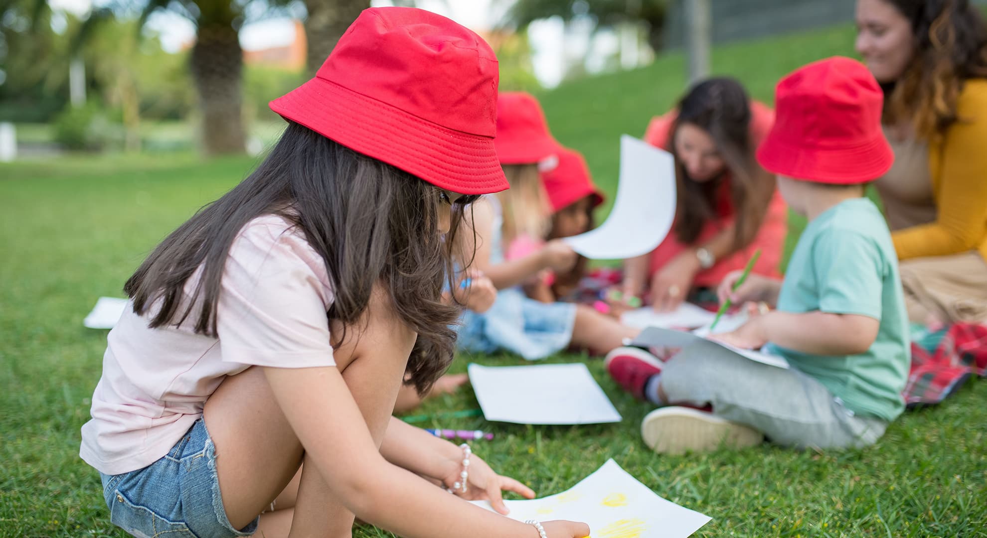 Young kids sitting on grass, drawing.