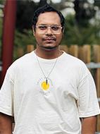 Photo of a dark haired man in a white t-shirt outdoors