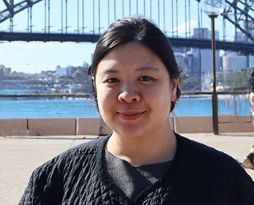 Image of a woman with dark tied-back hair with sydney harbour in the background