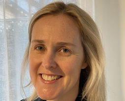 Image of a smiling woman with blonde hair and a black jacket