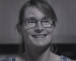 Image of a woman with hair up and glasses with blue top