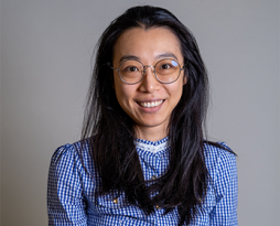 Image of a woman with long dark hair and wearing glasses and blue-check shirt