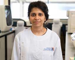 Photo of a young woman in the lab wearing a white labcoat