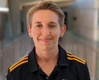 Photo of a person with short dark blonde hair in a black polo shirt