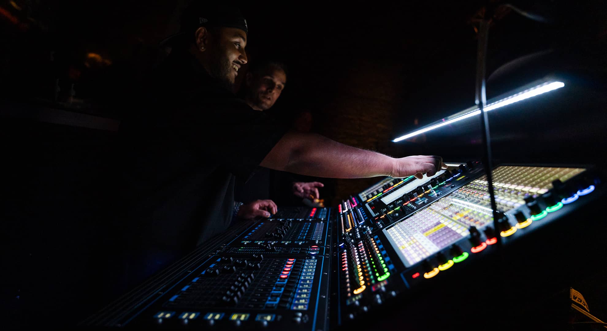 Two people working on a sound/lighting desk.